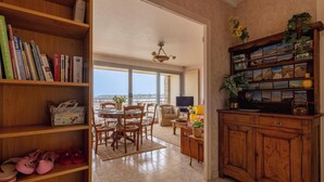 Un'ampia zona giorno con balcone, scaffali in legno, un tavolo da pranzo e una televisione.