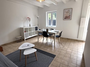 A dining area with a white table, black chairs, a white cabinet, and a window with a view. - NEW LISTING, Domaine de KER-PAULT, between St Cast and Matignon, 3-room cottage 5 minutes from... (MATIGNON)
