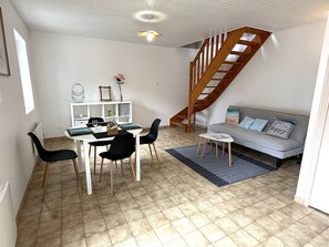 A modern living room with a dining area, a staircase, and a sofa with decorative pillows. - NEW LISTING, Domaine de KER-PAULT, between St Cast and Matignon, 2-bedroom apartment 5 minutes... (MATIGNON)