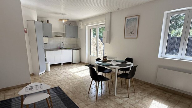 A modern kitchen with white cabinets, a dining table with chairs, and a window with a view of trees. - NEW LISTING, Domaine de KER-PAULT, between St Cast and Matignon, 2-bedroom apartment 5 minutes... (MATIGNON)