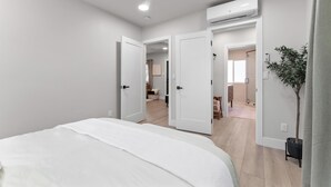 Ein Schlafzimmer mit Bett, weißen Wänden und einer Klimaanlage.