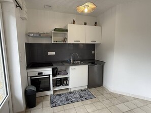 A compact kitchen with white cabinets, a black countertop, a stainless steel dishwasher, and a patterned rug. - NEW, Domaine de KER-PAULT, between St Cast and Matignon, studio apartment 5 minutes from the beaches (MATIGNON)
