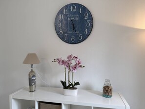 A wall clock, a lamp, a potted orchid, and a jar on a white console table. - NEW, Domaine de KER-PAULT, between St Cast and Matignon, studio apartment 5 minutes from the beaches (MATIGNON)