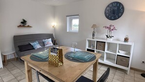 Una sala de estar moderna con una mesa de comedor, sofá y un reloj decorativo en la pared.
