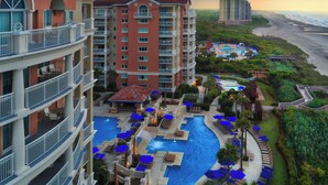Ein Hotel mit mehreren Etagen, einem Schwimmbad und Blick auf den Strand.