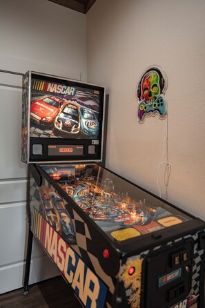 Eine Flipper-Maschine mit NASCAR-Branding und einer Totenkopf-Dekoration an der Wand.
