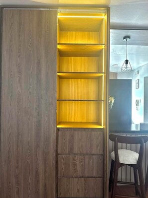 A room with a wooden cabinet, a dining table with chairs, and a pendant light. - Modern, Central and Cozy | San Isidro (San Isidro)