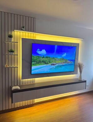 Ein Flachbildfernseher an der Wand montiert, mit integriertem Ablagefach und einer kleinen Pflanze.