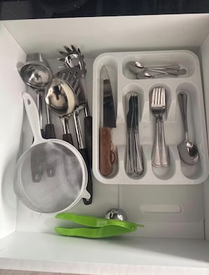 A box containing various kitchen utensils including spoons, forks, knives, and a strainer. - Modern, Central and Cozy | San Isidro (San Isidro)