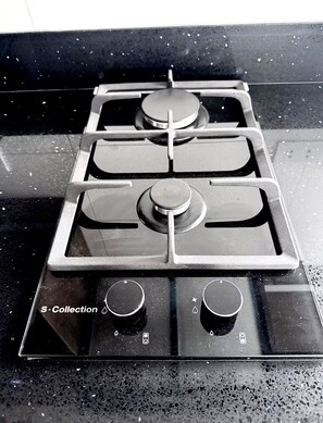 A gas stove with four burners and a control panel with three knobs. - Modern, Central and Cozy | San Isidro (San Isidro)