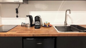 Et køkken med kaffemaskine, elkedel og en kurv med krydderier på bordet.