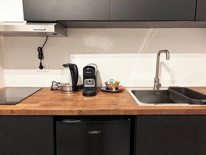 Una cucina con una macchina da caffè, un bollitore e un cesto di condimenti sul piano di lavoro.