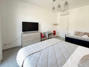 Una camera da letto con un letto, una TV, una scrivania e una sedia.