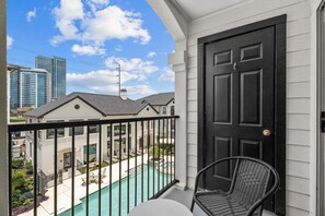 Un balcone con vista su una piscina, una porta e una sedia.