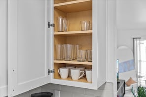 A kitchen cabinet with clear glassware and white mugs. - 2302 Cortland (Houston)