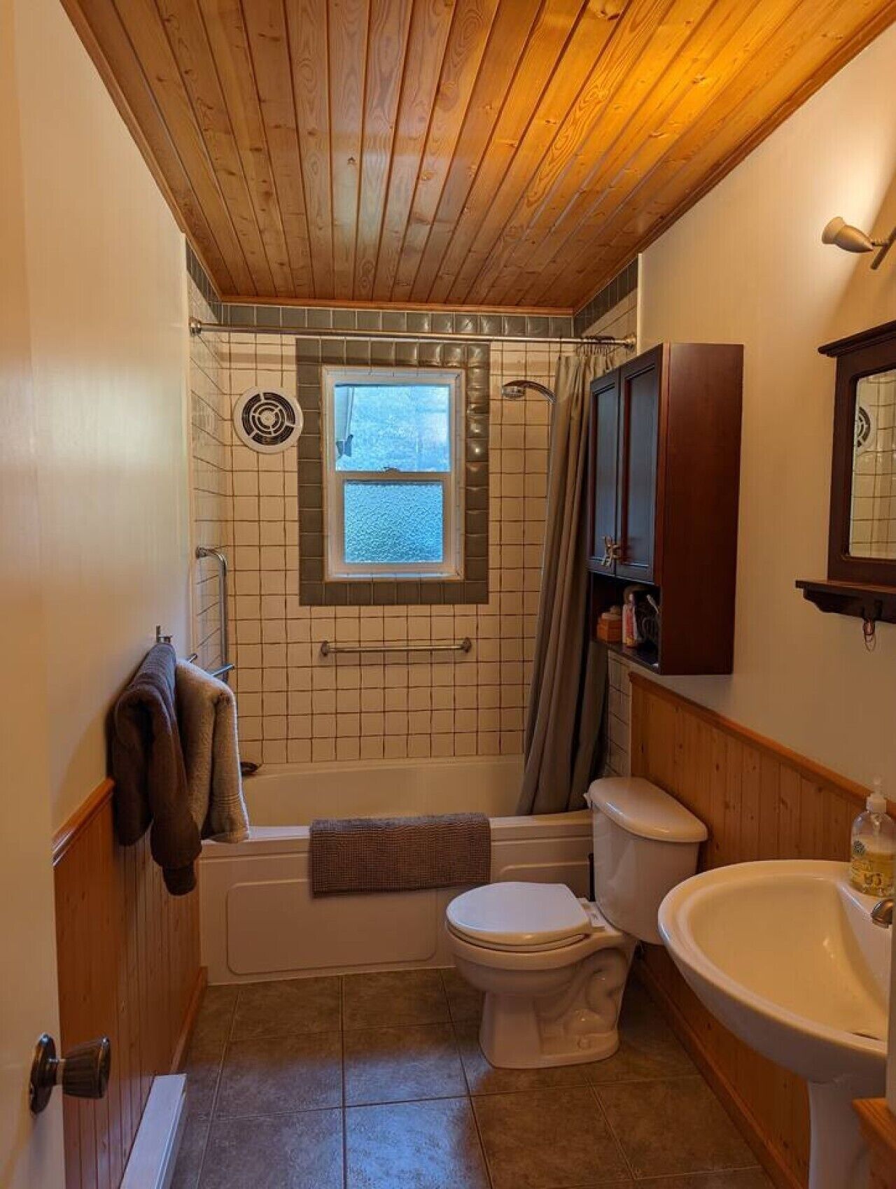 Une salle de bain avec un plafond en bois, une baignoire, des toilettes et un lavabo.