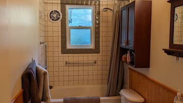 Une salle de bain avec un plafond en bois, une baignoire, des toilettes et un lavabo.