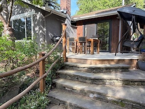 A wooden staircase leading to a covered outdoor area with a table and chairs.