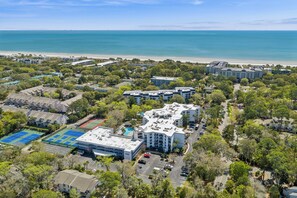 An aerial view of a coastal hotel complex with multiple buildings, a beach, and tennis courts. - Ground level Villa with Community Indoor & Outdoor Pool + Free Activities! (Hilton Head Island)