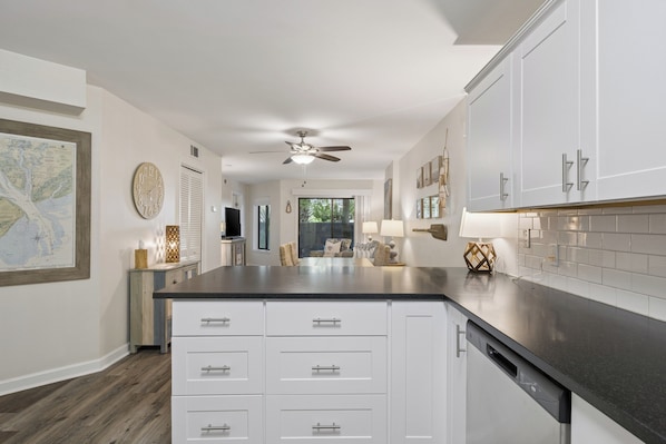 A modern kitchen with white cabinetry, a black countertop, and a ceiling fan. - Ground level Villa with Community Indoor & Outdoor Pool + Free Activities! (Hilton Head Island)