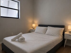 A neatly made bed with white linens, two bedside lamps, and a window with blinds. - Casa Hard Rock - Sleeps 14+Games+15 min to FTL (Miramar)