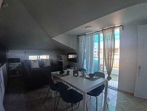 Ein modernes Wohnzimmer mit Essbereich, einem Flachbildfernseher und einer Schiebeglastür nach draußen.