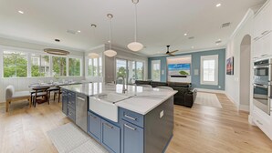 Uma cozinha espaçosa com uma ilha grande, eletrodomésticos modernos e muita luz natural.