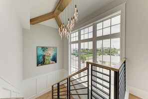 Eine Treppe mit hölzernen Geländern und Blick ins Freie durch große Fenster.