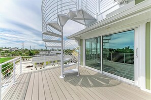 Eine moderne Terrasse mit Wendeltreppe, Glasschiebetüren und Blick auf die Umgebung.
