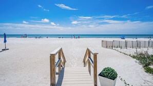 A wooden pathway leading to a beach with a clear sky.