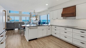 A modern kitchen with white cabinetry, a central island, and a view of the ocean.