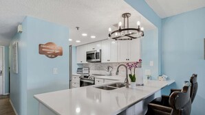 A modern kitchen with white cabinets, a central island with a sink, a stainless steel range, and a microwave. - Waterview #105 - condo with tranquil Intracoastal views in Indian Shores. (Indian Shores)