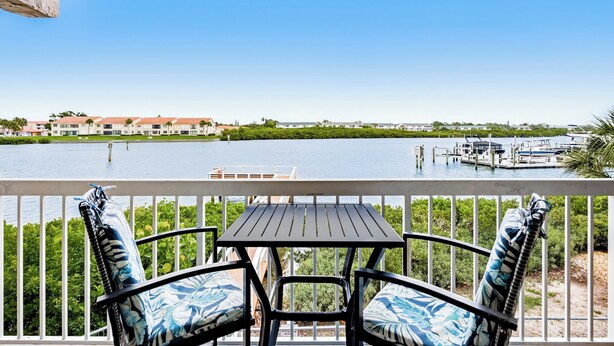 A balcony with a table and chairs, overlooking a marina with boats and buildings in the background. - Waterview #105 - condo with tranquil Intracoastal views in Indian Shores. (Indian Shores)