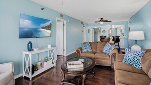 A living room with a television, a coffee table, and two sofas with patterned cushions. - Waterview #105 - condo with tranquil Intracoastal views in Indian Shores. (Indian Shores)