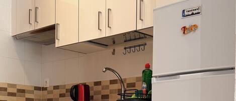 A kitchen with white cabinets, a stainless steel refrigerator, a dishwasher, and a tiled backsplash.