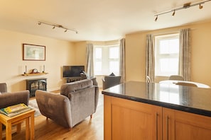 Ein Wohnzimmer mit Fernseher, Sofa und Holztisch.