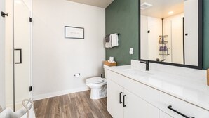 Un baño con inodoro, lavabo, espejo y zona de ducha.