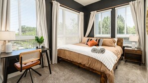 Un dormitorio con cama, mesitas de noche, escritorio y silla.