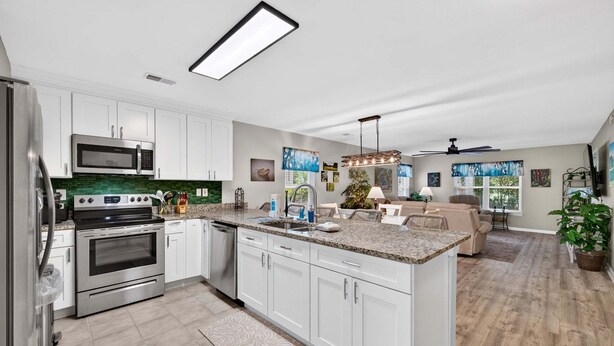 A modern kitchen with white cabinets, stainless steel appliances, and a large island. - First Floor condo on True Blue Golf course with Pool!!! (Pawleys Island)