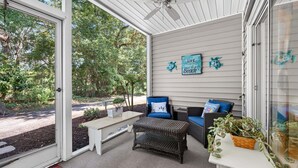 A covered porch with wicker furniture, a bench, and a wall sign. - First Floor condo on True Blue Golf course with Pool!!! (Pawleys Island)