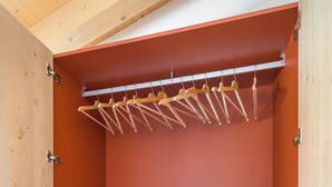 Un armadio con grucce in legno, un elettrodomestico e due cassetti.