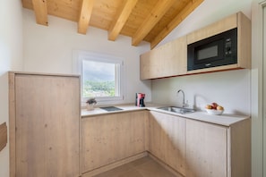 Eine Küche mit Holzausstattung, einer Mikrowelle, einem Spülbecken und einem Fenster mit Blick.