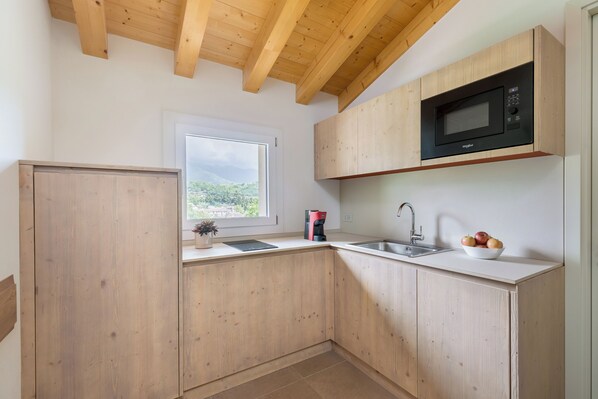 Eine Küche mit Holzausstattung, einer Mikrowelle, einem Spülbecken und einem Fenster mit Blick.