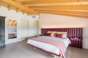 Ein Schlafzimmer mit einem großen Bett, Holzbalken, einem Kleiderschrank und einem Spiegel.