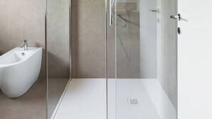 Un bagno moderno con cabina doccia in vetro, lavabo a piedistallo bianco e bidet.