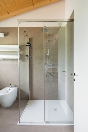 Ein modernes Badezimmer mit einer einteiligen Duschkabine, einem weißen Waschbecken auf Säule und einem Bidet.
