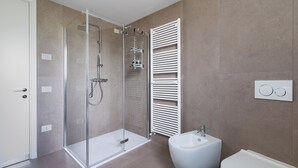 Un bagno moderno con doccia vetrata, lavandino a piedistallo bianco e water.