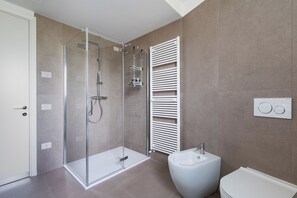 Ein modernes Badezimmer mit einer Duschkabine, einem weißen Waschbecken auf Säule und einer Toilette.