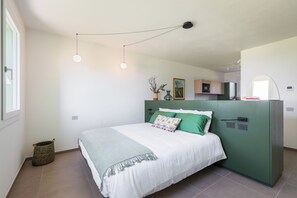 Ein Schlafzimmer mit einem Bett, einem grünen Kleiderschrank, einem kleinen Fenster und einer Wandleuchte.