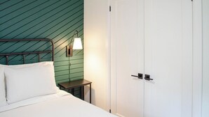 A bed with pillows, a bedside table, a lamp, and a white door. - Nature's Playground - Three Bedroom Cottage, Sleeps 6 (Gravenhurst)